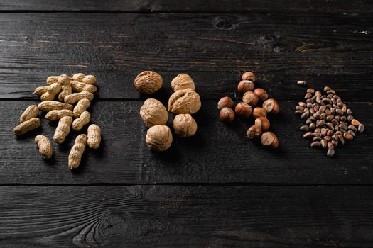 Different kinds of nuts, peanut, walnut, pine nuts and hazelnut set, on black wooden table background, with copy space for text