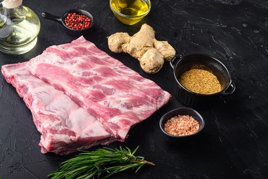 Fresh raw pork ribs with rosemary and garlic set, on black stone background