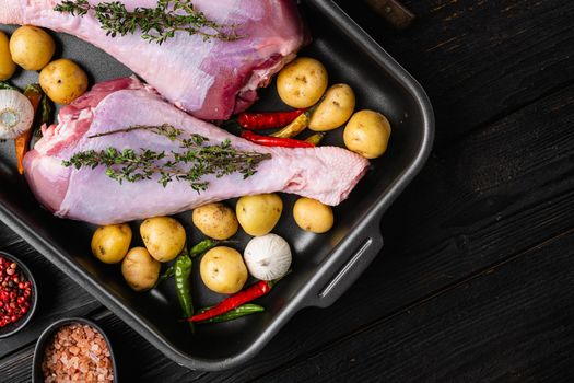 Raw turkey thigh with spices set, on black wooden table background, top view flat lay, with copy space for text