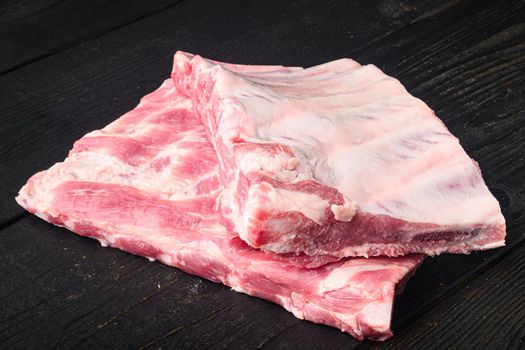 Rack of raw pork spare ribs set, on black wooden table background