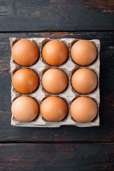Fresh eggs on paper egg box set, on old dark wooden table background, top view flat lay