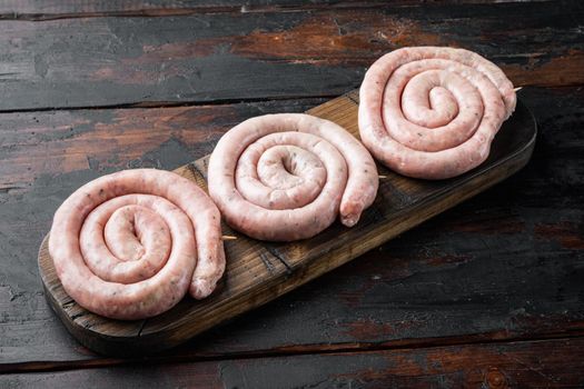 Traditional raw spiral pork sausages set, on old dark wooden table background