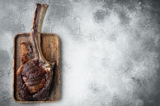 Barbecue dry aged Tomahawk Steak beef meat set, on wooden serving board, on gray stone background, top view flat lay, with copy space for text