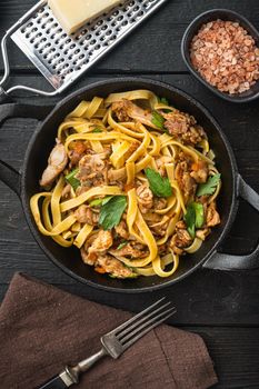 Pasta with rosemary rabbit stew set, in frying cast iron pan or pot, on black wooden table, top view flat lay