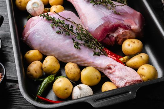 Fresh turkey legs with ingredients for cooking set, on black wooden table background