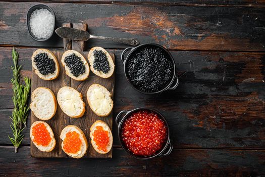 Canapes with black sturgeon, and salmon fish caviar, on old dark wooden table background, top view flat lay