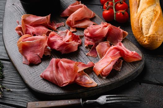 Jamon serrano. Traditional Spanish ham, on black wooden background