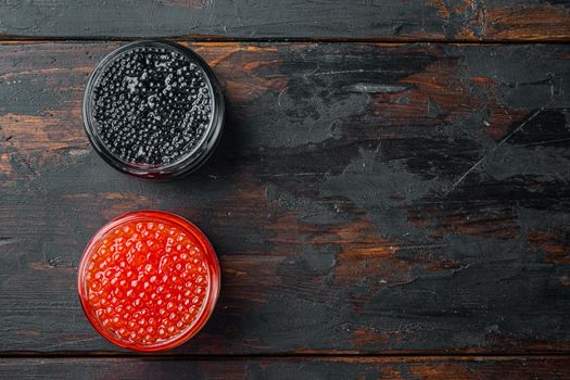 Red and black caviar in glass bowl, on old dark wooden table background, top view flat lay with copy space for text