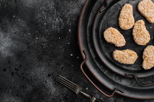 Instant food raw chicken nuggets ready for cooking, on black dark stone table background, top view flat lay, with copy space for text