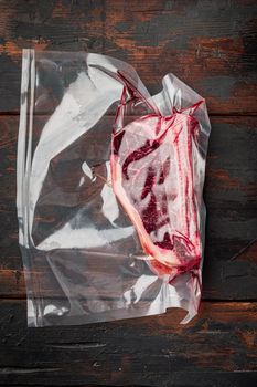 Fresh marbled meat black angus steak in vacuum plastic bag for sous vide set, on old dark wooden table background, top view flat lay