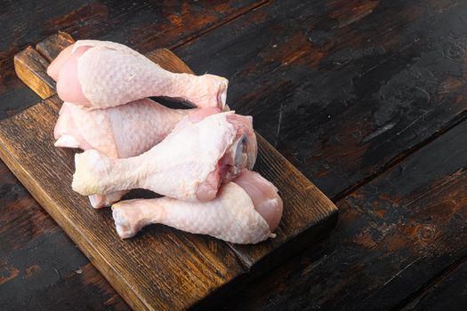 Chicken brow and drumstick with skin set, on wooden cutting board, on old dark wooden table, with copy space for text