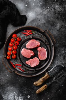 Raw pork fillet, on black dark stone table background, top view flat lay