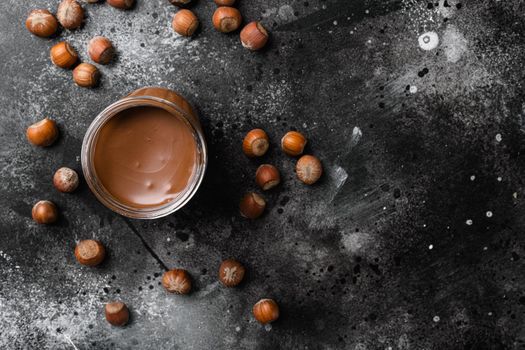 Chocolate hazelnut in jar with nuts set, on black dark stone table background, top view flat lay, with copy space for text