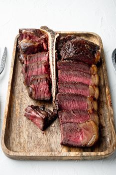 American cuisine. Sliced and roast T-bone or porterhouse beef medium rare meat Steak set, on white stone background