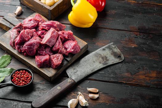 Fresh beef chunks served on table with ingredients ready for cooking set with sweet bell pepper, on old dark wooden table, with copy space for text