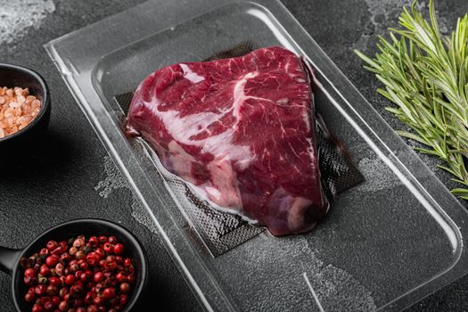 Vacuum black plastic pack with rump beef meat cut set, on black dark stone table background