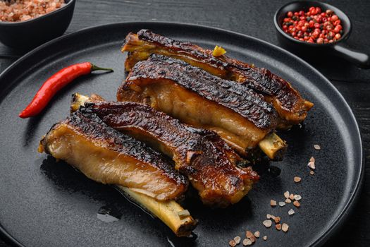 Grilled pork ribs with rosemary and honey set, on plate, on black wooden table background