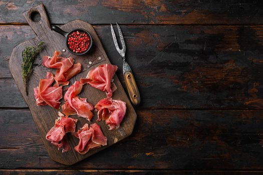 Spanish cold meat jamon, on old dark wooden table background, top view flat lay, with copy space for text