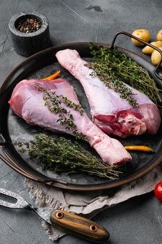 Raw turkey drumsticks with thyme, pepper set, on gray stone table background