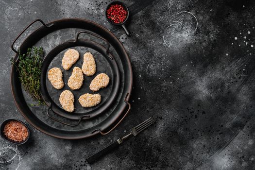 Chicken nuggets uncooked, on black dark stone table background, top view flat lay, with copy space for text