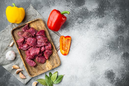 Raw veal beef for stew set with sweet bell pepper, on gray stone background, top view flat lay, with copy space for text