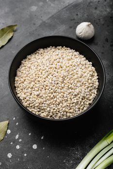 Raw pile of pearl barley set, on black dark stone table background