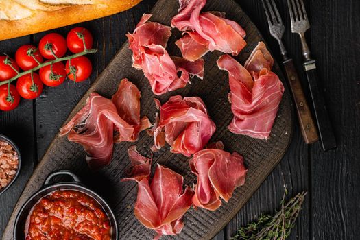 Spanish cold meat jamon, on black wooden background, top view flat lay
