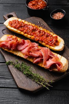 Italian tomato, prosciutto, jamon, ham and cheese bruschetta set, on black wooden table background