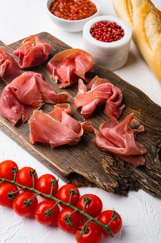 Slices of prosciutto di parma or jamon serrano, on white stone table background