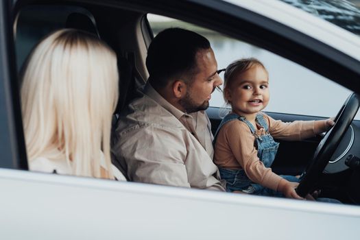 Father Showing His Little Daughter How to Drive Car, While Mother Sitting on Passenger Seat, Family on Road Trip