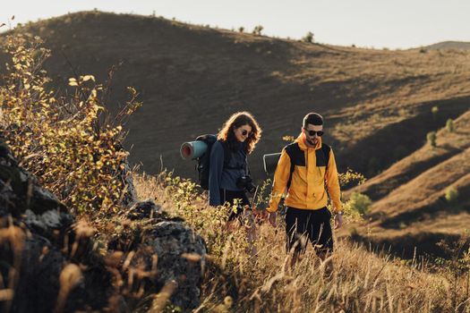 Man and Woman Holding by Hands While Hiking Together on Hill During Sunset, Young Couple Enjoy Their Trip