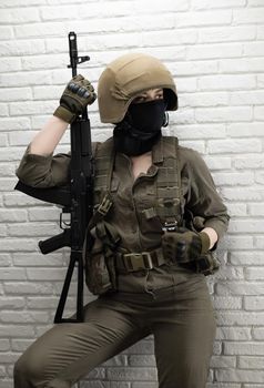 soldier girl in a helmet is sitting and talking on a mobile phone