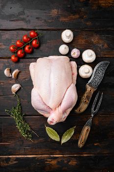 Whole raw chicken set, on old dark wooden table background, top view flat lay