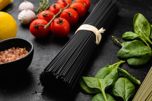 Squid ink black tinted twirl of raw tagliatelle set, on black dark stone table background