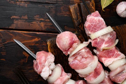 Fresh raw meat pieces on skewers set, top view flat lay, with copy space for text, on old dark wooden table background