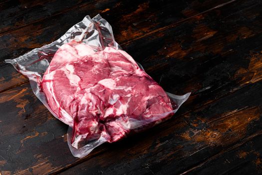Vacuum packed meat set, on old dark wooden table background, with copy space for text