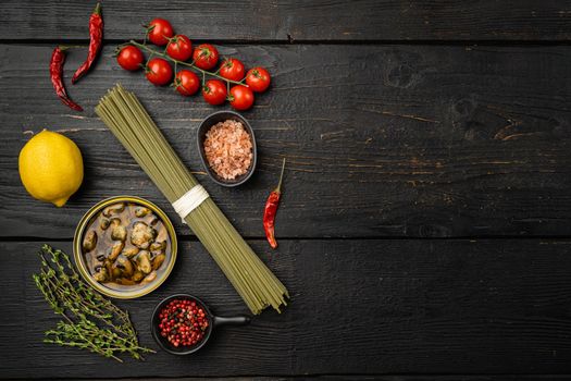 Ingredients for preparation spaghetti with calms or mussels set, on black wooden table background, top view flat lay, with copy space for text