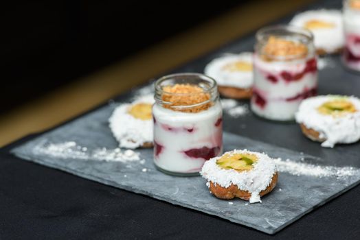 little bun with a dessert in a glass cup, with Jello, yogurt and topping. Mini desserts.