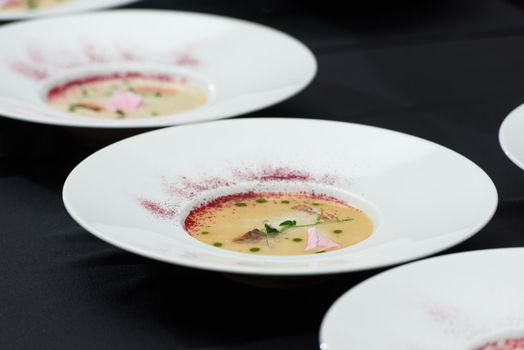 fish cream soup with salmon, cheese and herbs in white soup bowls.