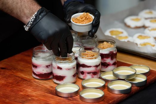 Chief preparing dessert in a glass cup, with Jello, yogurt and topping. Mini desserts.