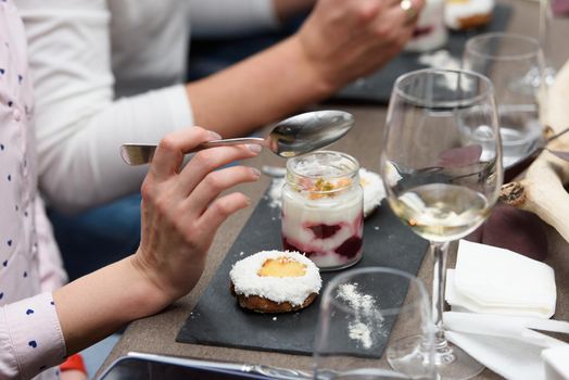 Woman eats dessert in a glass cup, with Jello, yogurt and topping served in a restaurant. Mini desserts.