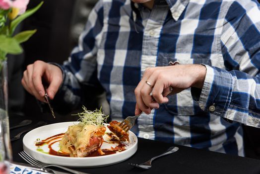 Man eating Francesinha, traditional Portuguese sandwich in a restaurant. National cuisine concept.