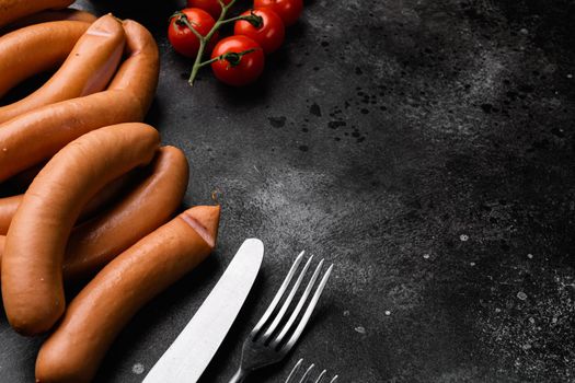 Raw barbecue sausages set, on black dark stone table background, with copy space for text