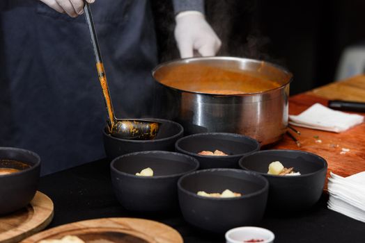 cooking process of Suquet de Peix soup with potatoes, herbs and fish with the addition of picada close-up in a saucepan on the table. horizontal