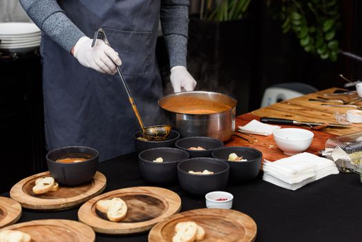 cooking process of Suquet de Peix soup with potatoes, herbs and fish with the addition of picada close-up in a saucepan on the table. horizontal