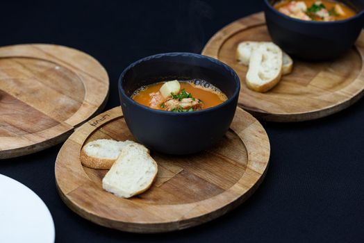 Seafood spicy soup with potatoes, shrimps, mussels, herbs and fish from a picad closeup in a pan served with toast. horizontal