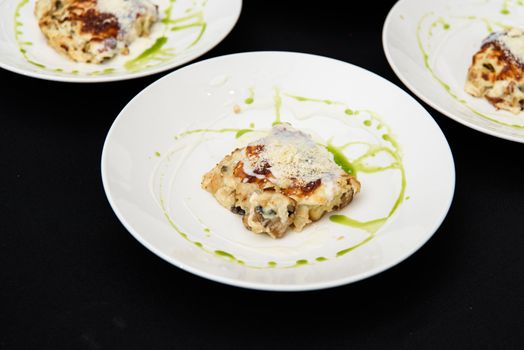 Chief serving potato gratin with chanterelles mushrooms and cheese in a restaurant.