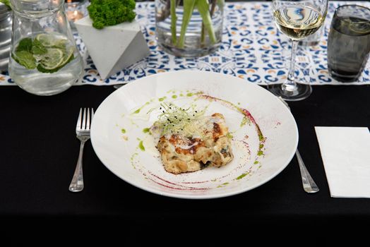 Portion of potato gratin with chanterelles mushrooms and cheese in a restaurant.