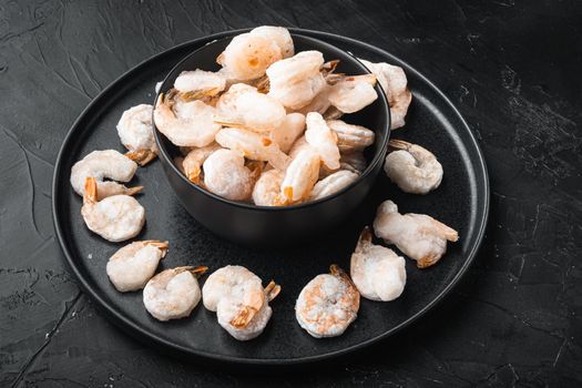 Boiled and frozen shrimps set, in bowl, on black stone background