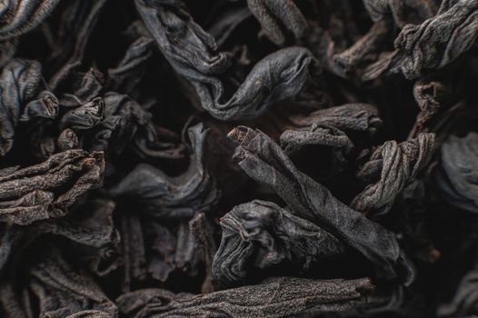 Extreme macro Black loose leaf tea as a background. Texture of dry black tea leaves in shallow depth of field. Dark background. macro mode. black leaf tea closeup.